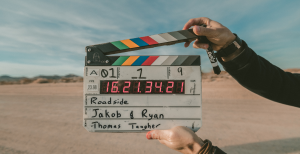 a person holding up a clapper board in the desert